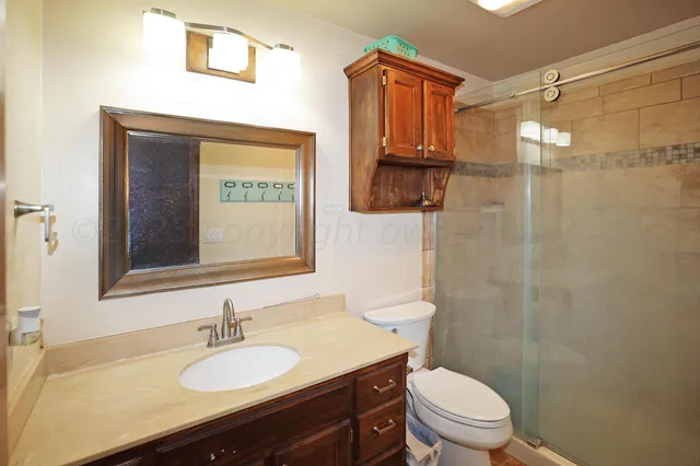 a bathroom with a granite countertop sink toilet a mirror and shower