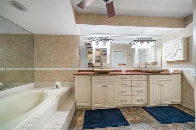 a spacious bathroom with a granite countertop tub a double vanity sink and a mirror