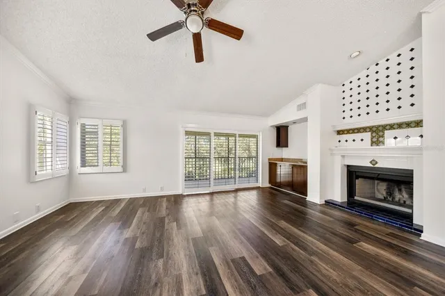 a view of an empty room with wooden floor fireplace and a window
