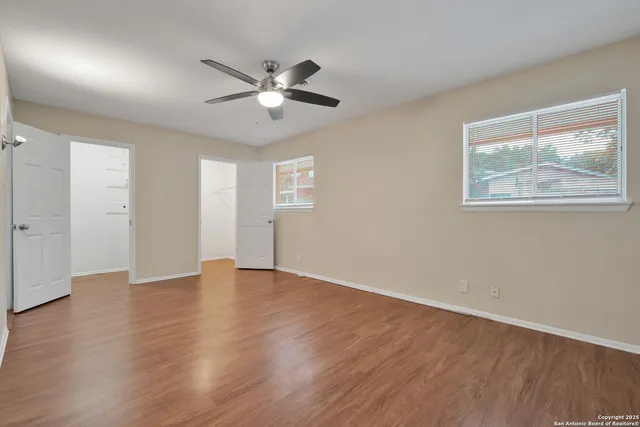 a view of an empty room with wooden floor and a window