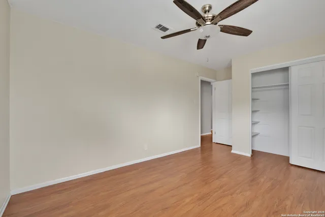 an empty room with wooden floor and ceiling fan
