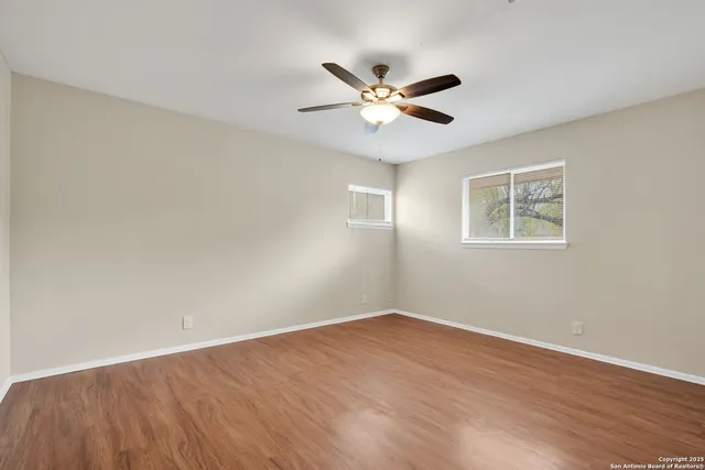 a view of an empty room with wooden floor and a window