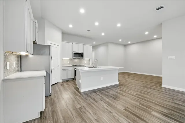a view of kitchen with cabinets stainless steel appliances with wooden floor
