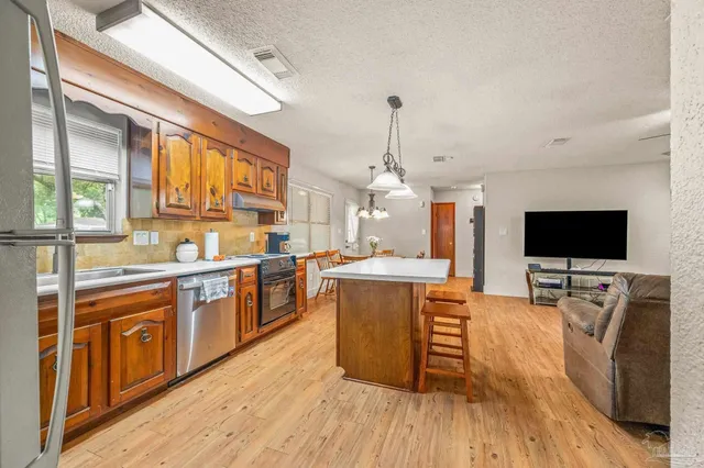a living room with stainless steel appliances furniture and a flat screen tv