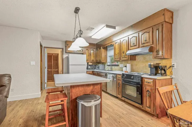 a kitchen with stainless steel appliances granite countertop a sink a stove and a wooden floors