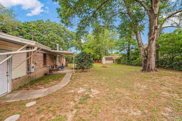 a view of a house with backyard and a tree