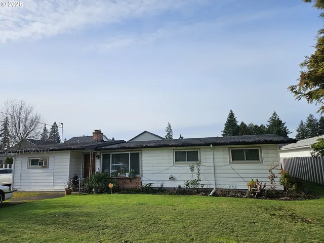 a view of a yard in front of a house with plants and large tree