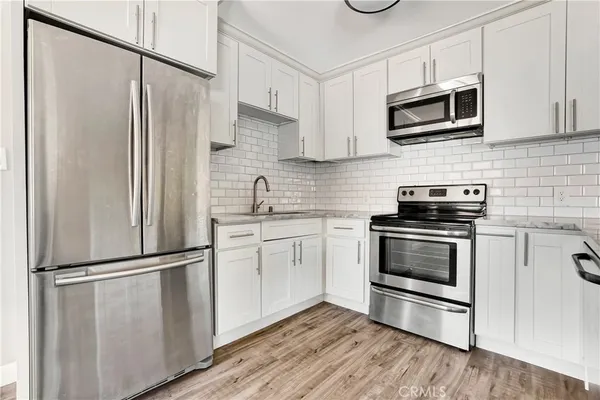 a kitchen with cabinets stainless steel appliances and wooden floor