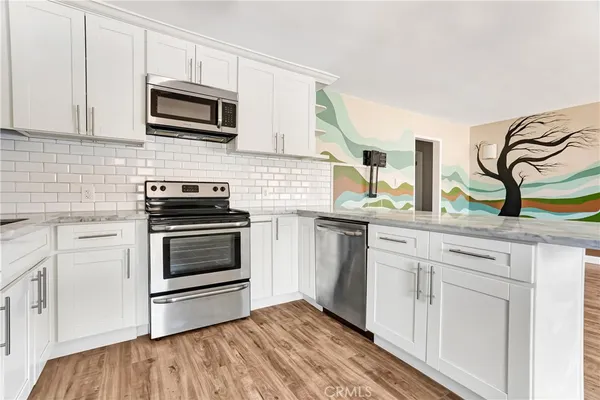 a kitchen with granite countertop a stove top oven microwave and cabinets
