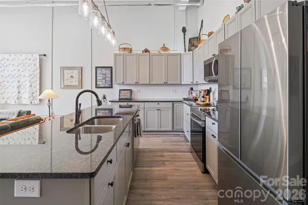 a kitchen with stainless steel appliances granite countertop a stove a sink and white cabinets