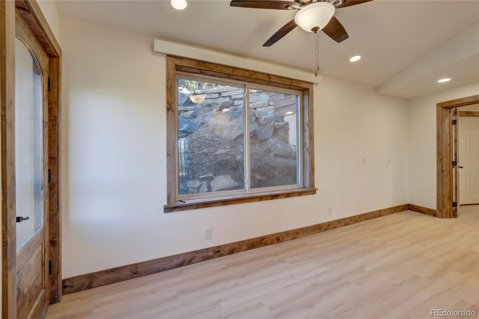 85 Santa Fe Mountain Road Evergreen, CO 80439 - Photo 18 of 47 an empty room with wooden floor fan and windows