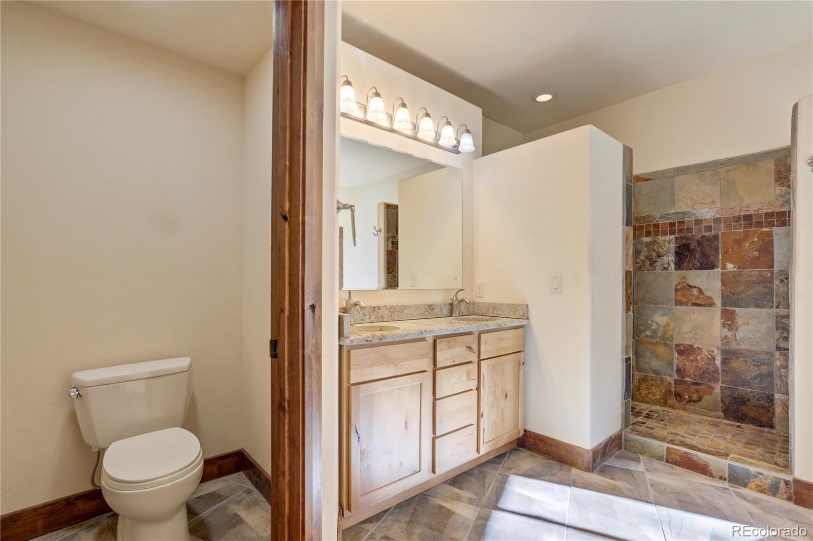 85 Santa Fe Mountain Road Evergreen, CO 80439 - Photo 9 of 47 a bathroom with a granite countertop sink mirror vanity and toilet