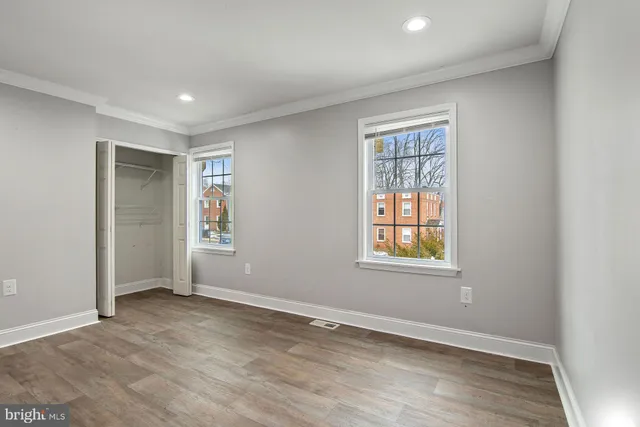 an empty room with wooden floor and windows