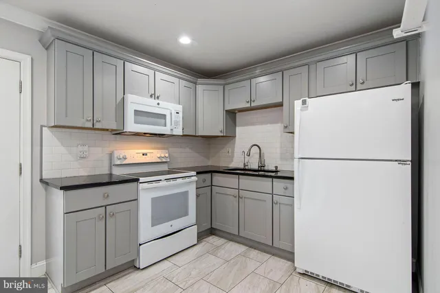 a kitchen with sink a refrigerator and white cabinets