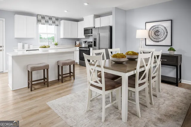 a kitchen with stainless steel appliances granite countertop a dining table chairs refrigerator and sink