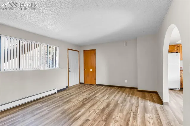 a view of an empty room with wooden floor and a window