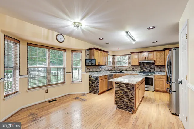 a kitchen with a refrigerator a stove top oven a sink dishwasher and white cabinets with wooden floor