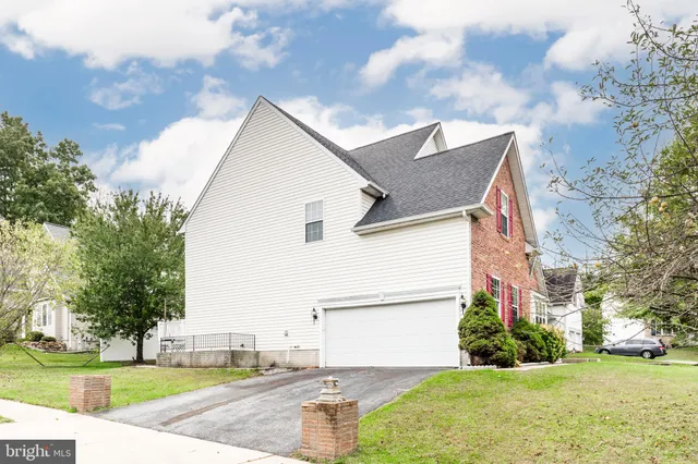 a view of a white house next to a yard with big trees