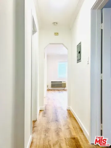 a view of a hallway with wooden floor and a bathroom