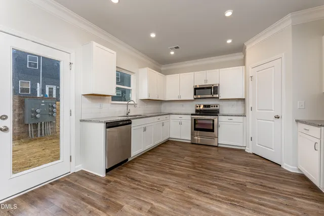 a kitchen with granite countertop a refrigerator and a stove top oven