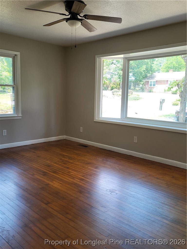 182 Summerhill Road Fayetteville, NC 28303 - Photo 11 of 24 an empty room with wooden floor a ceiling fan and windows