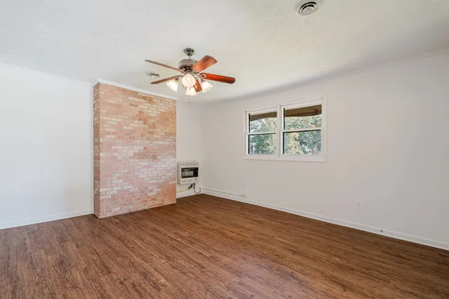 an empty room with wooden floor chandelier fan and windows