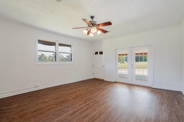 a view of an empty room with wooden floor and a window