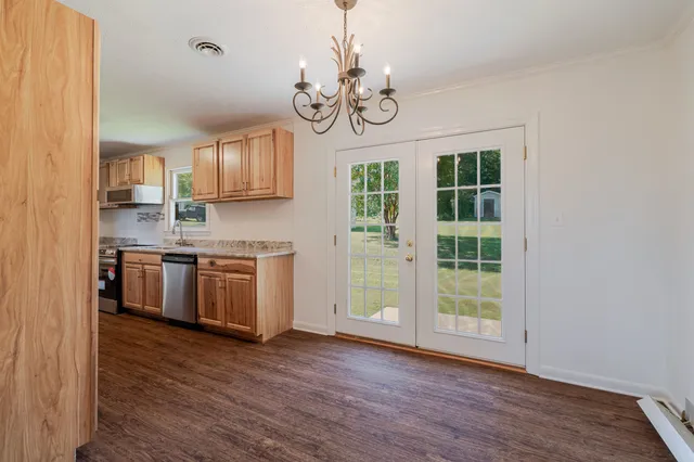 a kitchen with stainless steel appliances granite countertop a stove a sink dishwasher a refrigerator and a dining table with wooden floor