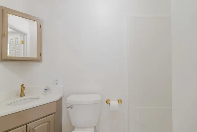 a bathroom with a toilet sink vanity and mirror