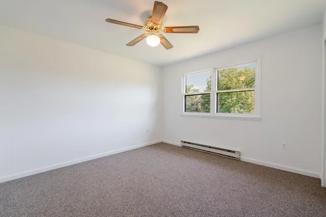 an empty room with a window and a ceiling fan