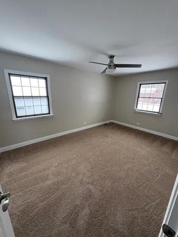 an empty room with windows and ceiling fan