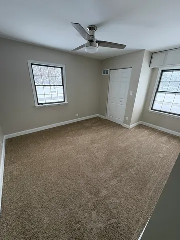 an empty room with windows and fan