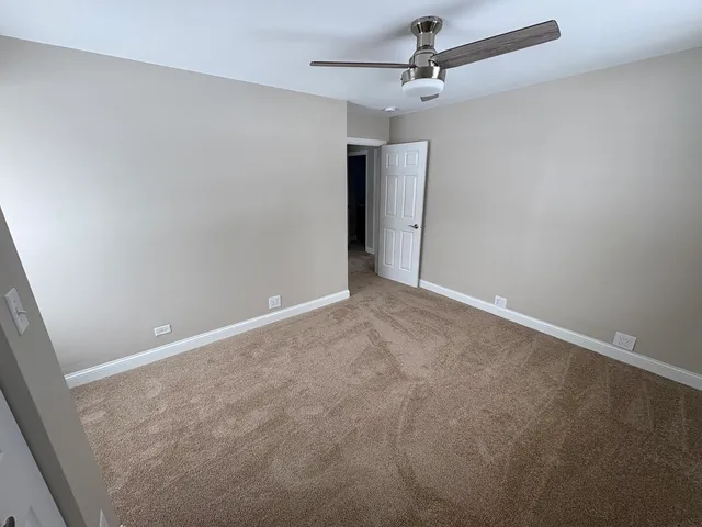an empty room with a ceiling fan and a window