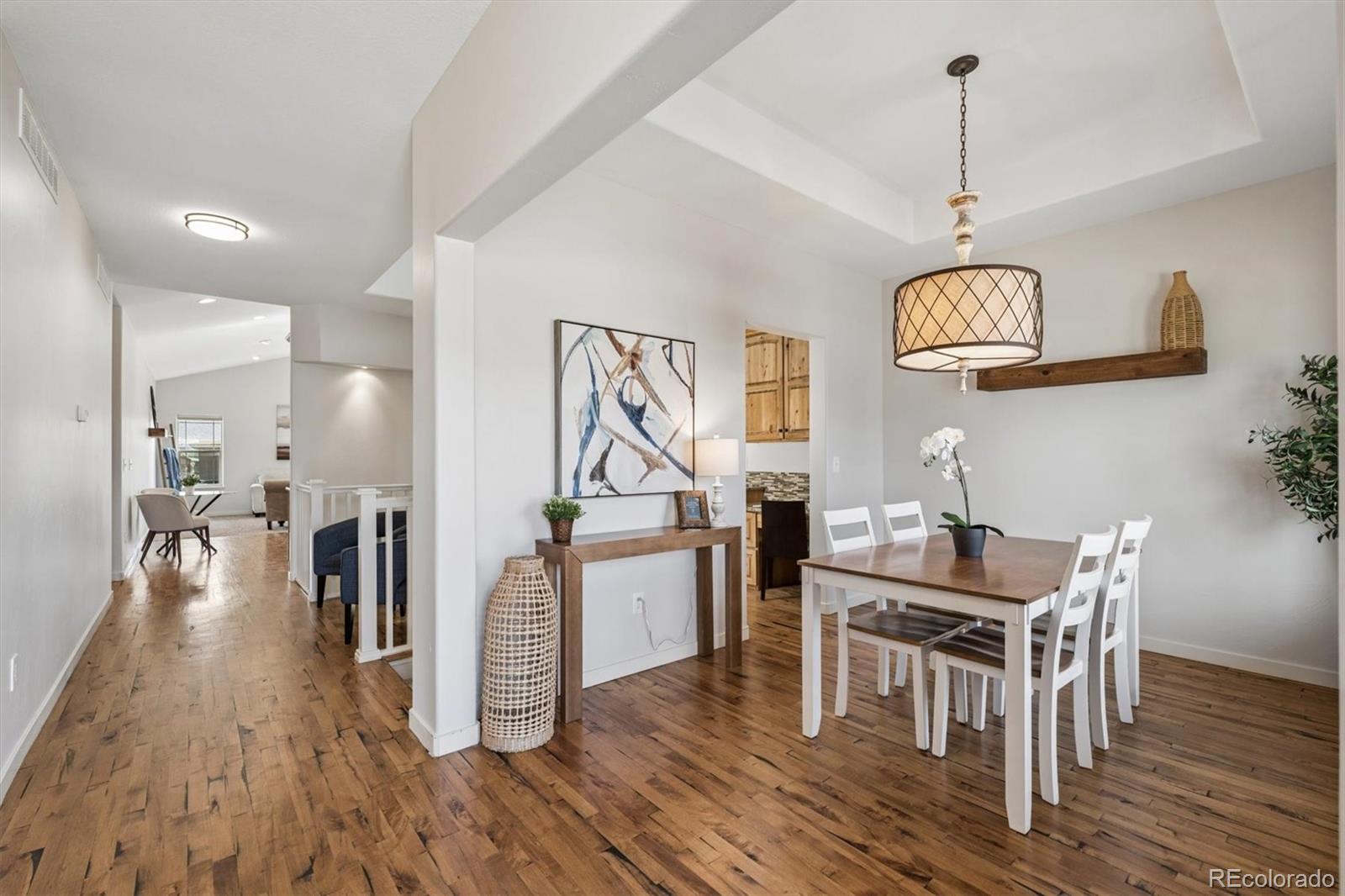 3674 Watts Street Timnath, CO 80547 - Photo 6 of 50 a dining room with wooden floor a chandelier a wooden table and chairs