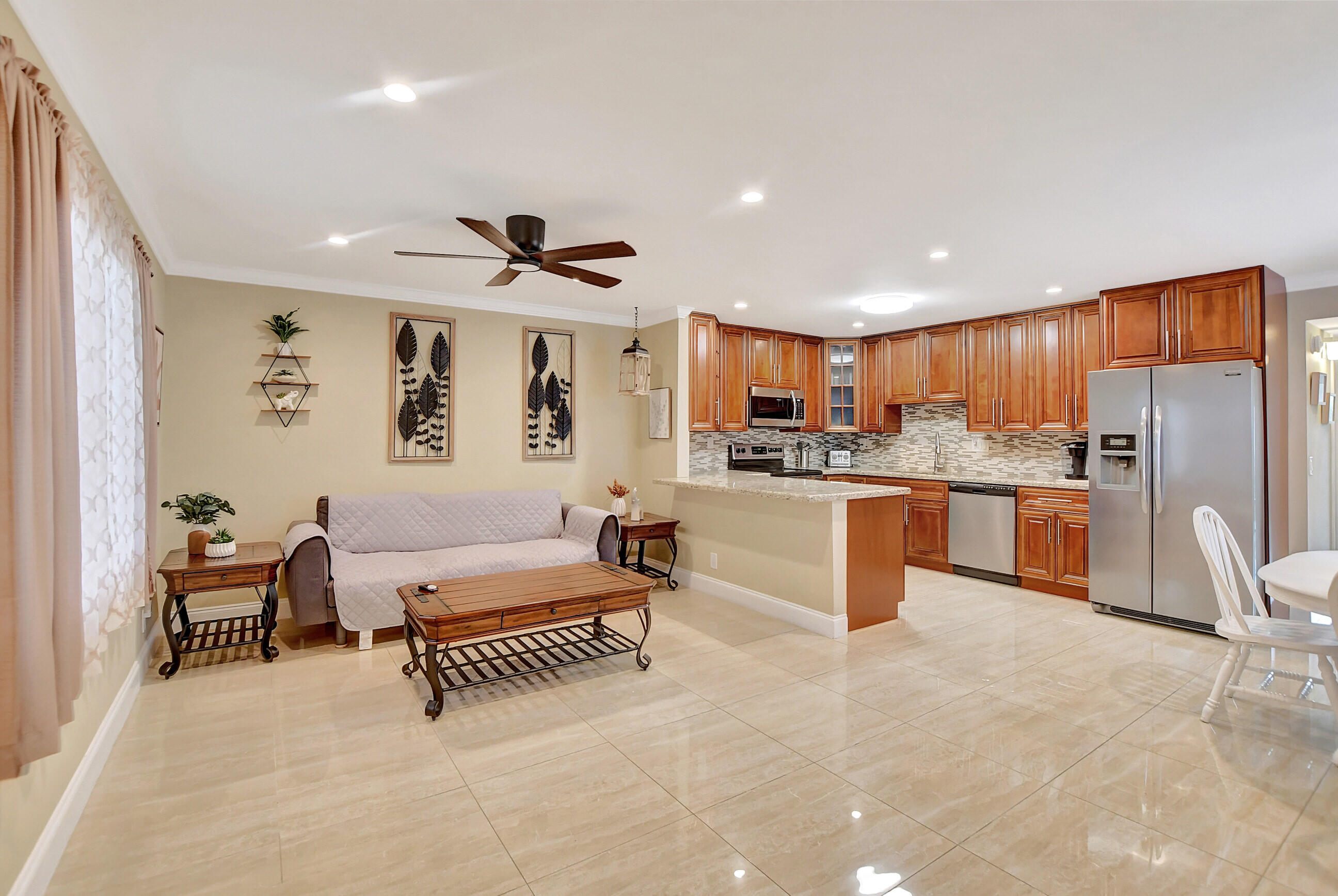 a large living room with stainless steel appliances kitchen island granite countertop furniture and a large window