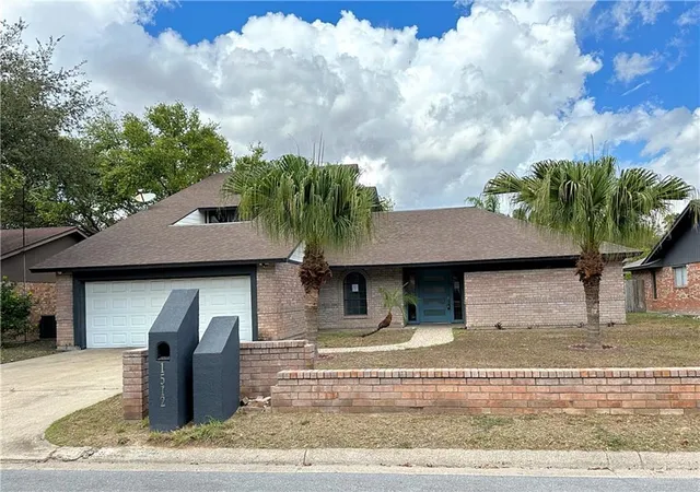 a backyard of a house with plants and palm tree