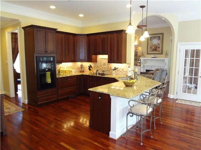 2059 Crescentview Road Pulaski, TN 38478 - Photo 7 of 20 a kitchen with kitchen island granite countertop wooden floors and wooden cabinets