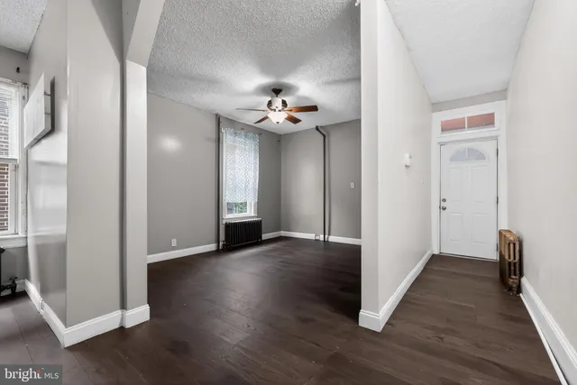 an empty room with wooden floor and a ceiling fan