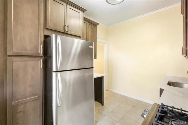 a view of a refrigerator in kitchen and an empty room