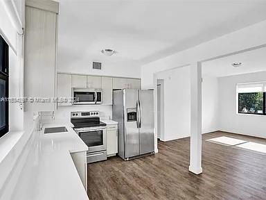 4203 Southwest 15th Street, Unit 2 Miami, FL 33145 - Photo 6 of 13 a kitchen with stainless steel appliances a stove a microwave and white cabinets