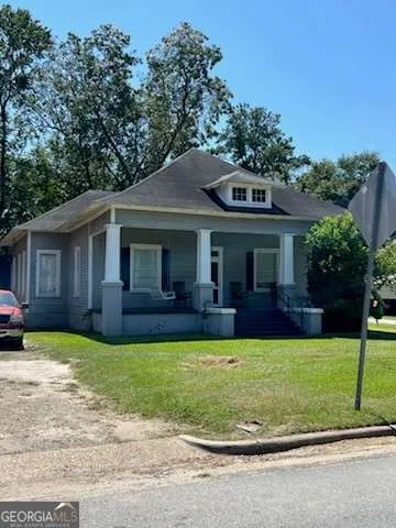 a view of a house with a yard and large trees