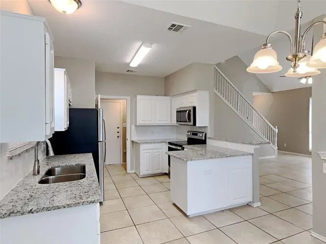 a view of an empty room with window and chandelier fan