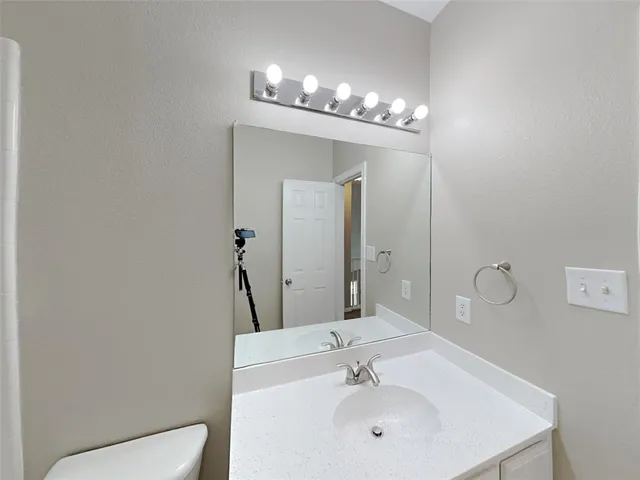 a bathroom with a sink mirror and toilet