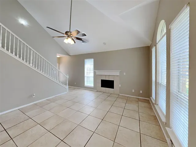 a view of an empty room with a fireplace and a chandelier fan