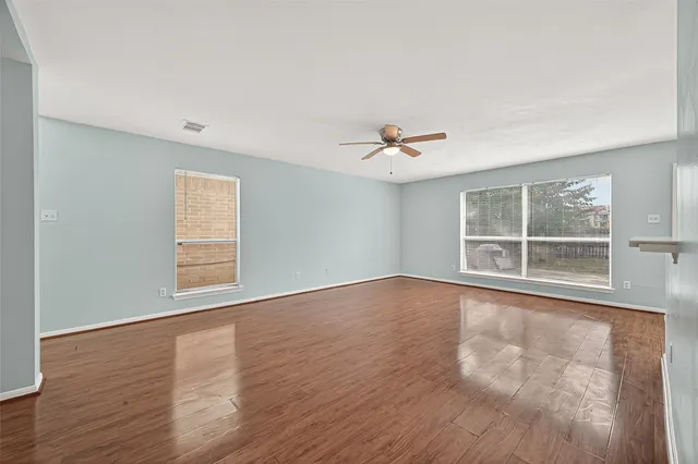 a view of an empty room with a window and wooden floor