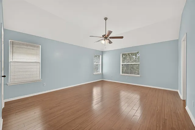 a view of an empty room with a window and wooden floor