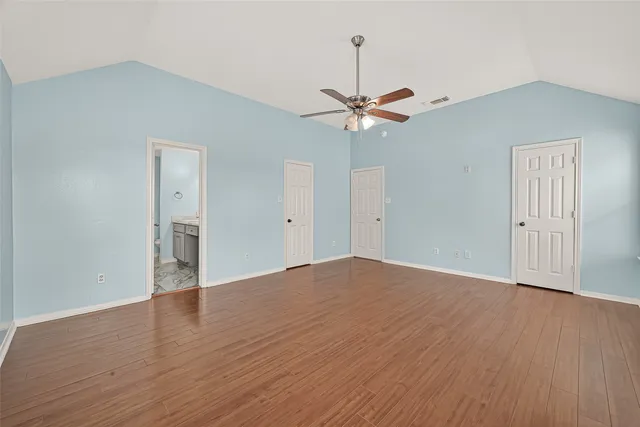 an empty room with wooden floor fan and windows