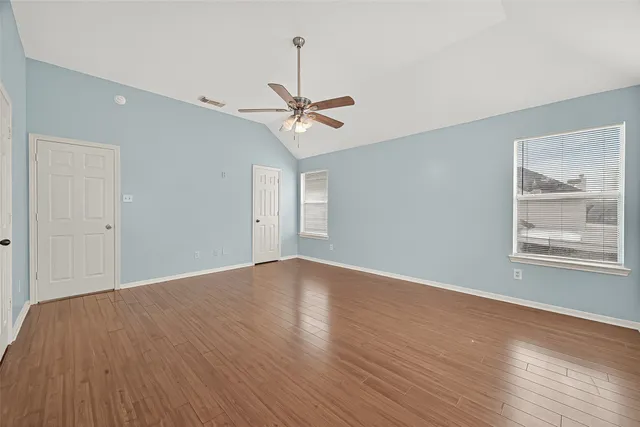 a view of an empty room with a window and wooden floor