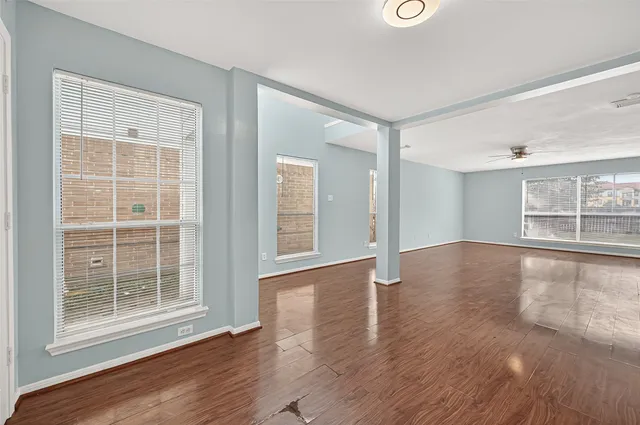 a view of an empty room with wooden floor and a window