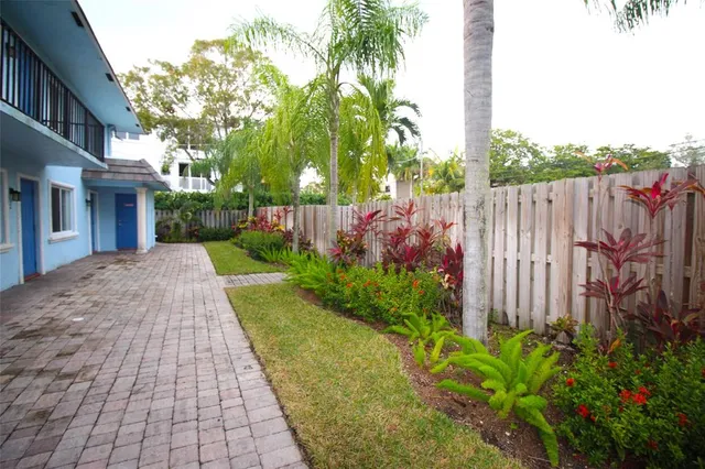 a view of a backyard with brick wall and potted plants